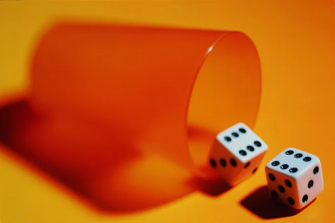 dice rolling out of an orange cup