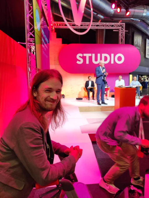 Matt McCann smiling in front of studio stage with Minister and judges on stage