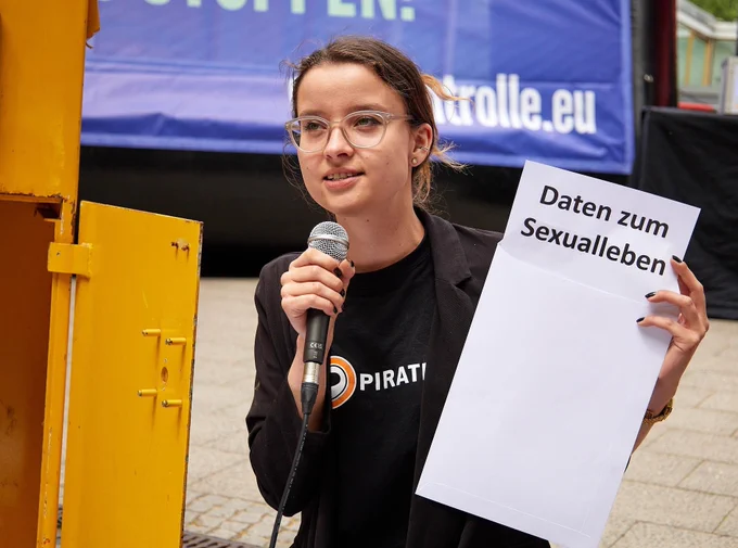 Anne hält neben dem offenen Briefkasten einen geöffneten Brief, auf dem "Daten zum Sexualleben" steht. 