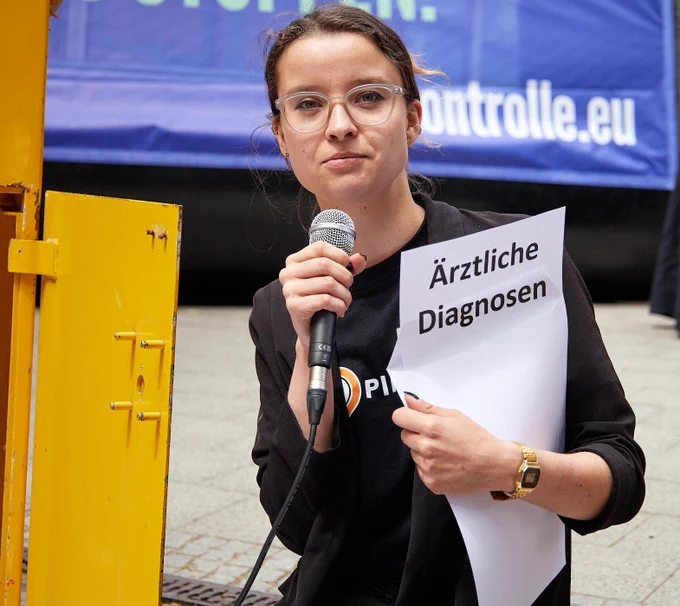 Anne hält neben dem offenen Briefkasten einen geöffneten Brief, auf dem "Ärztliche Diagnosen" steht. 
