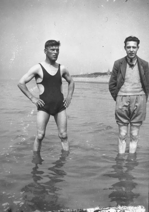 Black and white photo of two Fryston men standing in the sea off Scarborough beach, which almost comes up to their knees. One is in a rather revealing bathing suit, and looks a bit like an unamused Tommy Shelby. The other is more formally dressed but has rolled his trousers up past his knees. Photo taken by Jack Hulme, circa 1940s