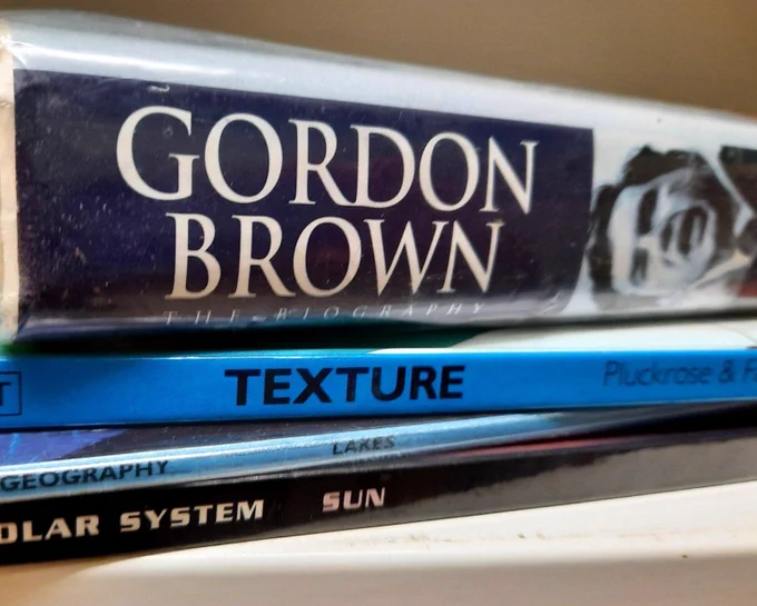 A stack of books with their spines showing. Gordon Brown, Texture, Lakes, Sun