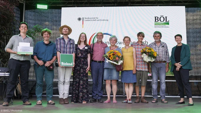 Gruppenbild der Arbeits- und Lebensgemeinschaft "Alles im Grünen Bereich e.V." aus Niederkaufungen während der Auszeichnung auf der Bühne.