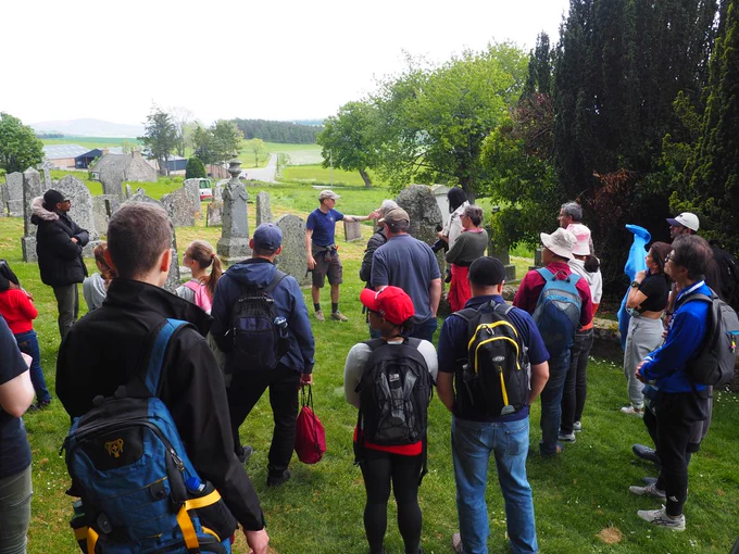 Group of people attentively listening to a speaker in a historic graveyard