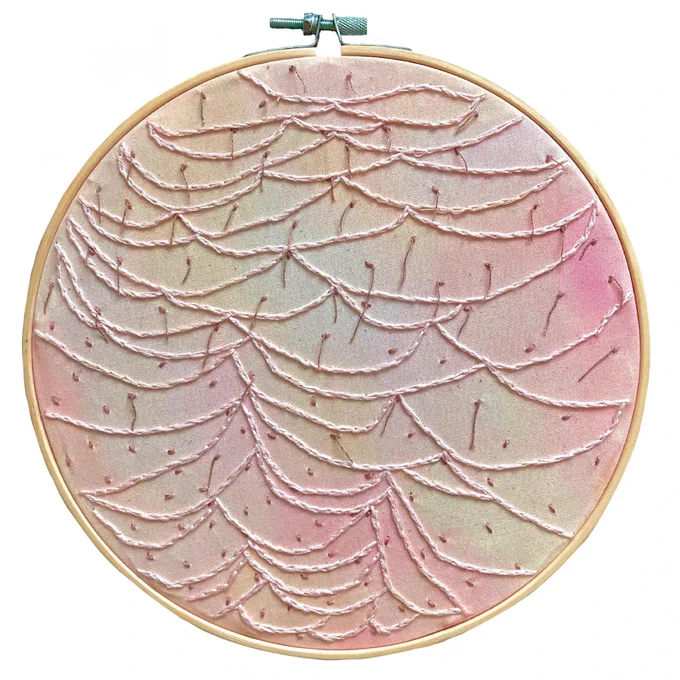 Artwork by Isobel Lawrence which shows fabric which has been embroidered and sits in a round embroidery hoop. It is a mixture of flesh tones from pinks and beiges and there are overlapping threads which create a pattern on the fabric.