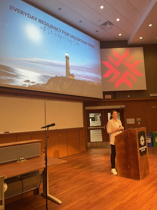 Dr. Robyne speaking at the podium at Fanshawe College in front of the slide: Everyday Resiliency for Uncertain Times.