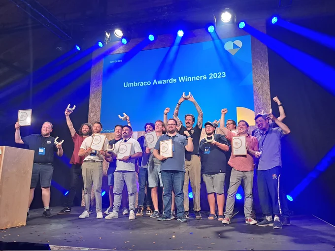 The winners of Umbraco Awards 2023 are posing for a picture on the Codegarden stage, holding their trophies in the air.