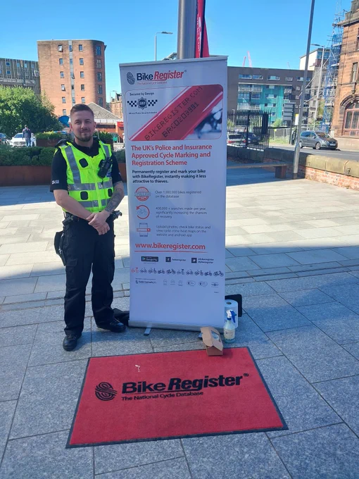 Police officer in city centre, Glasgow standing next to bike register banner