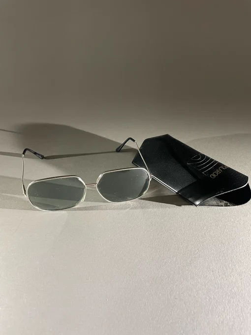 Photo of a pair of 1970s metal rimmed sunglasses with their case. 