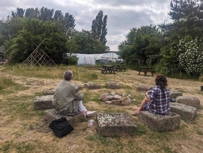 Two adults sit around a stone circle looking out on a garden