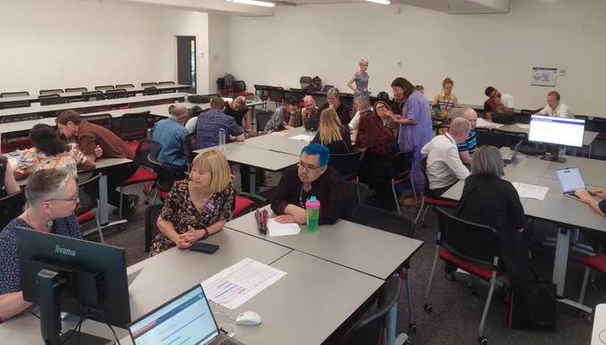 Crowd of people at tables, talking and engaging with activities