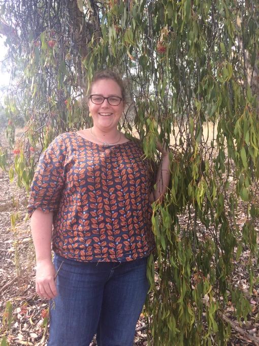 A woman standing in front of a cascade of leaves. They look like leaves from a tree, but actually they are a big mistletoe!