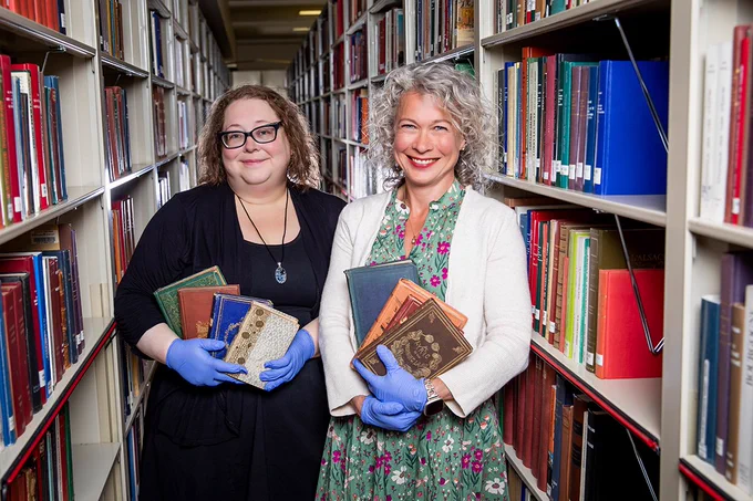 Shelby Strommer, the collections care coordinator for Preservation Services, and Jennifer Hain Teper, the head of Preservation Services for the University Library, hold Victorian-era books.

Photo by Michelle Hassel.