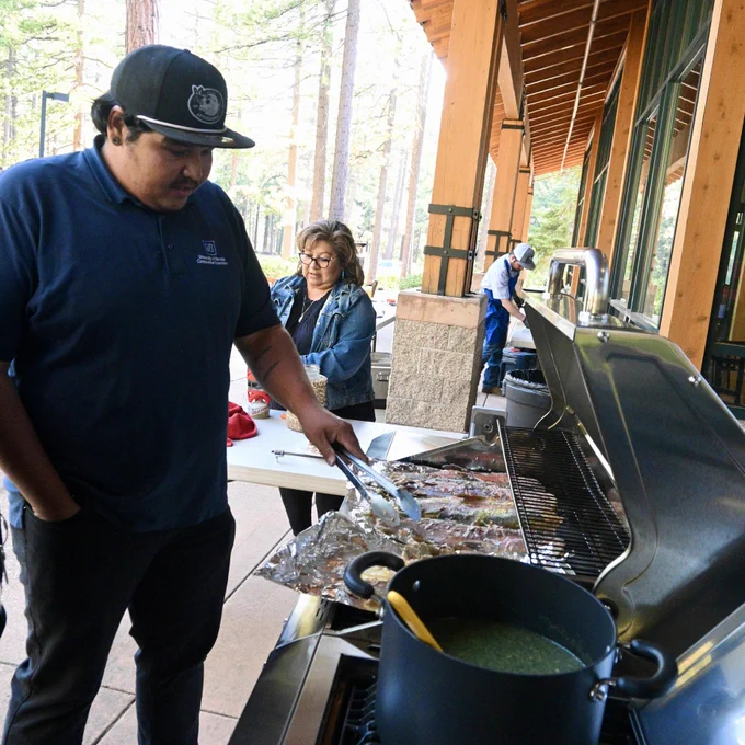 man cooks fish on outdoor grill