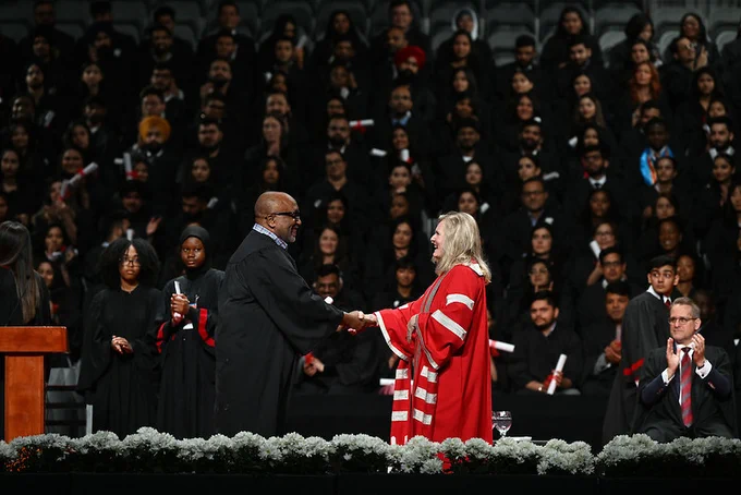 York President Rhonda Lenton shakes hands on stage during the School of Continuing Studies graduation ceremony.
