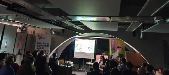 full house in the archives' reading room with a writer introducing the event in cosy pink armchair 
