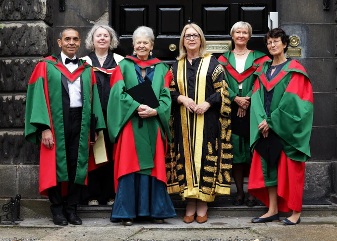 six people in colourful honorary degree gowns photographed in front of large door  left to right Provost Linda Doyle , Uǧur Şahin,, Joan Steitz, Mary McAleese, Beate Schuler and Özlem Türeci
