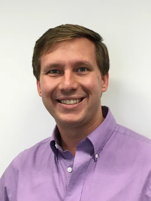 Prof. Christopher Muhich. He's smiling and in a lavender button-down shirt.