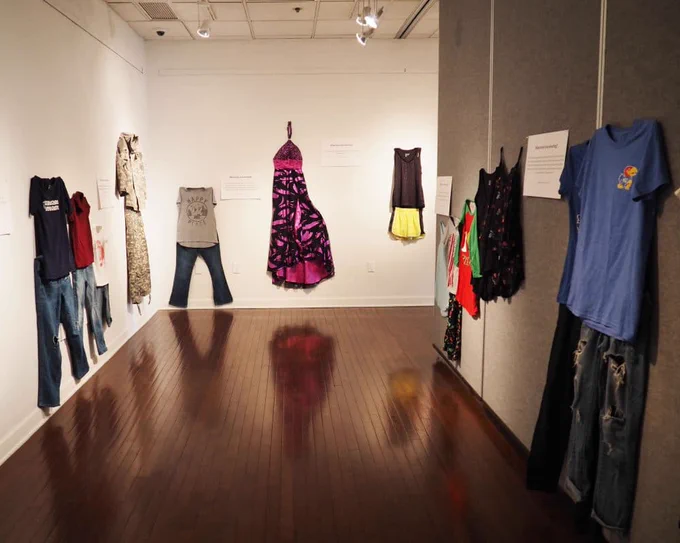 a variety of clothes in different sizes including a maxi dress and a t-shirt and jeans hung up on the wall.