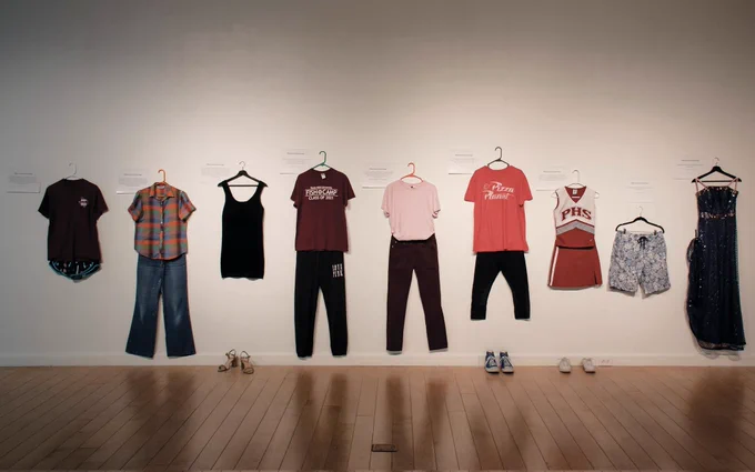 a variety of clothes in different sizes including t-shirts and leggings, dresses, and shorts hung up on the wall.