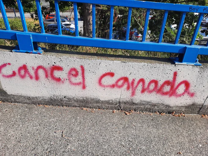 Cancel Canada in red graffiti on concrete fence base.