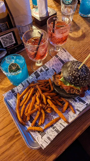 Picture of one blue cocktail (shiva) and 2 red Cocktails (Phoenix) below is the Eikonic burger and sweet potato fries. 