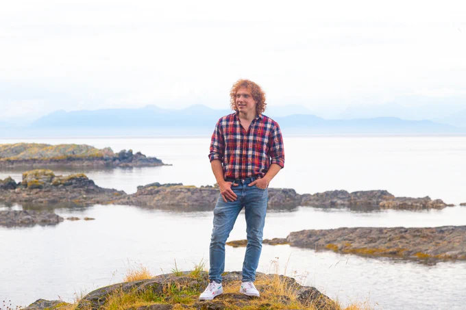 Ted stands on a bluff with the ocean behind him
