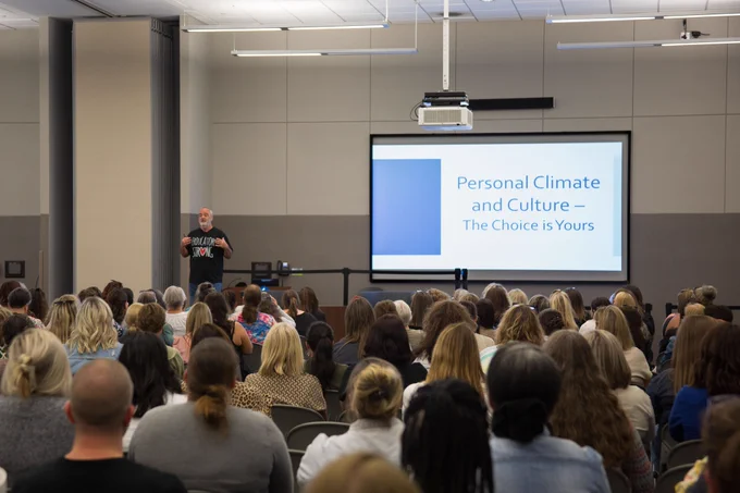 Gerry Brooks faces a room full of educators in front a a screen reading, "Personal Climate and Culture — The Choice is Yours."