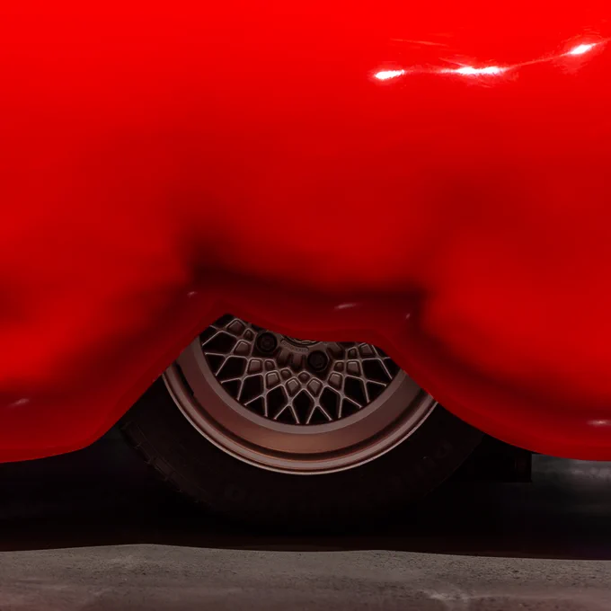 Close-up of a tyre, half covered by the exterior of the car which is thick, red and overflowing. 