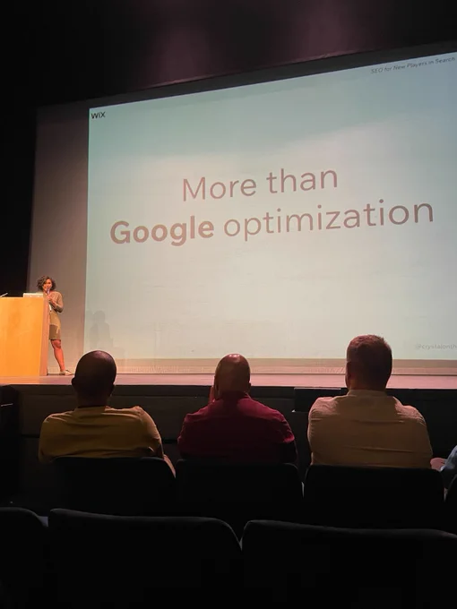 A woman standing on a stage speaking to an audience
