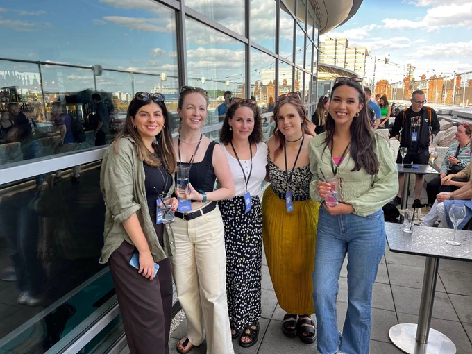 5 women stood in a bar wearing lanyards 
