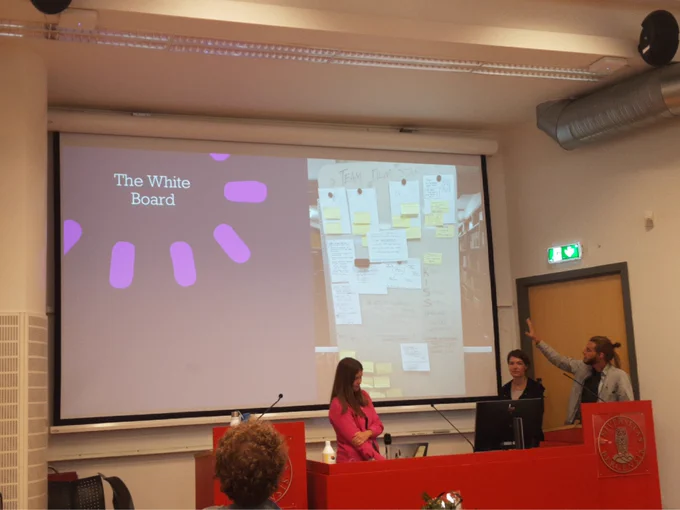 A group of people infront of a presentation inba lecture hall. Slide title: The whiteboard