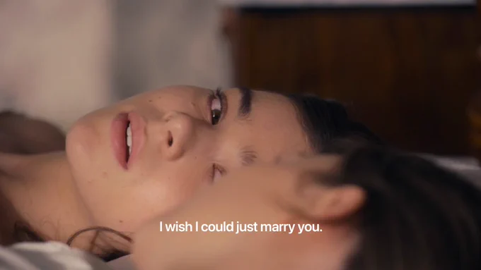 Emily Dickinson (played by Hailee Steinfeld) in the TV show "Dickinson" lays on a bed gazing lovingly at Sue Gilbert (played by Ella Hunt). The caption reads "I wish I could just marry you."