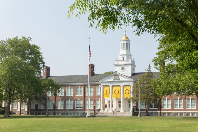 Rowan University Bunce Hall with brown and gold 100 banners hanging above the entry way. 