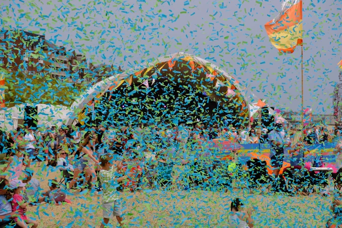 Blue confetti falls through the air, on the beach in front of the Sunlight Stage at First Light Festival