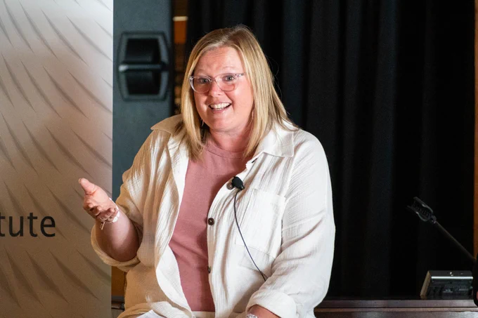 Kerri Whipple, Director of Literacy from South East Education Cooperative, sits on a stage and speaks to the audience.