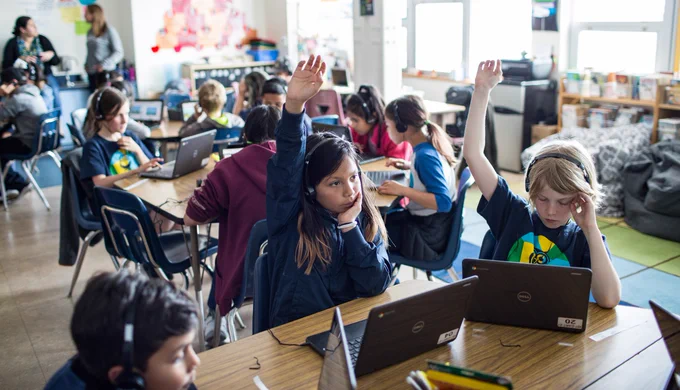 Photo of students raising their hands in class.
