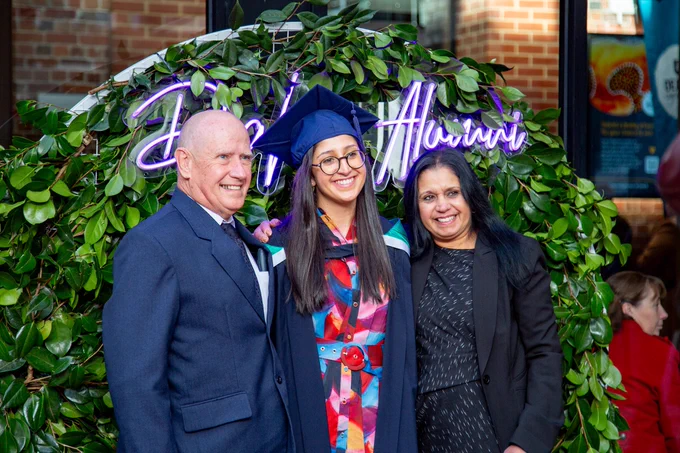 A Deakin student celebrating graduations and posing for a photo with family.
