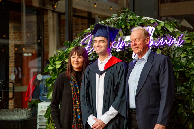 A Deakin student celebrating graduations and posing for a photo with family.