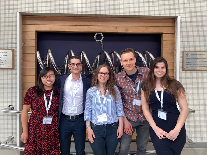 Three women and two men with conference badges in a line
