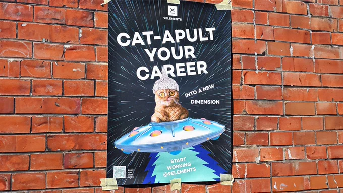 A Poster of a aluminumhat wearing cat with a confused look on their face. The Cat is sitting in a spaceship. On the Poster it's written: Cat-Apult your carreer into a new dimension. Start working @9elements