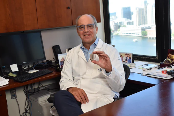 Christopher Hartnick, MD sits in his office holding up the Inspire hypoglossal nerve stimulator.