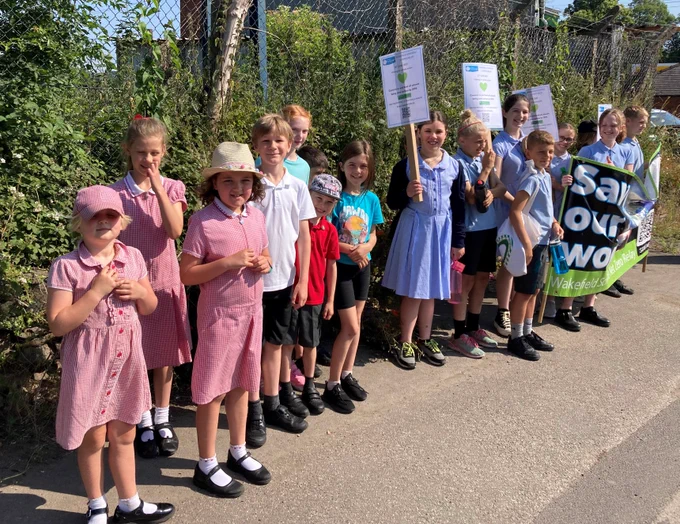 Children taking part in Wakefield Schools Climate Relay carrying a banner with the words save our world