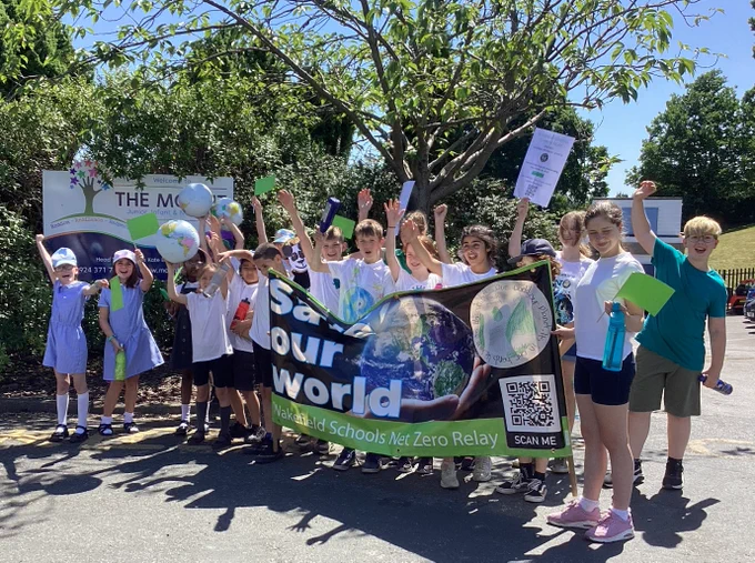 Children taking part in Wakefield Schools Climate Relay carrying a banner with the words save our world