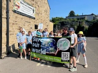 Children taking part in Wakefield Schools Climate Relay carrying a banner with the words save our world