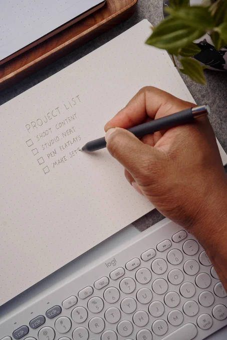 A hand holding a Mark Three, writing on a Panobook.
