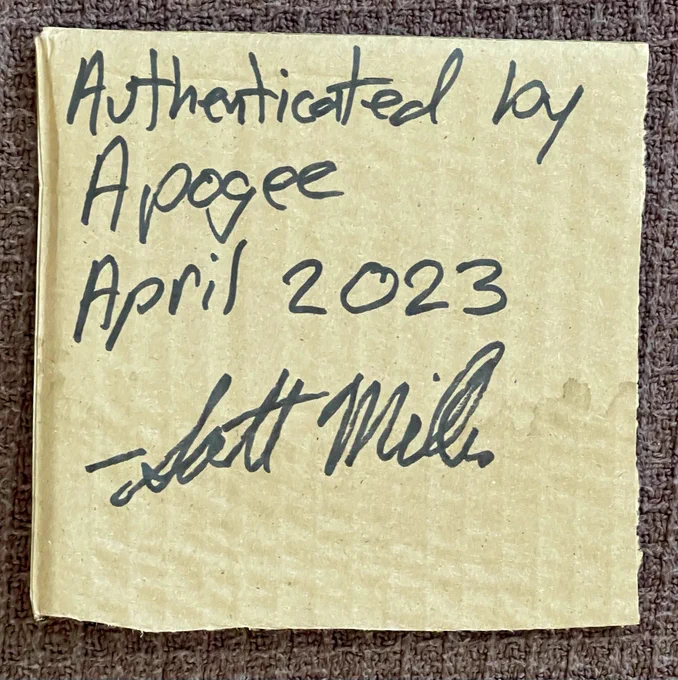 The reverse side of the cardboard with writing from Apogee's Scott Miller.

"AUTHENTICATED BY APOGEE APRIL 2023
- SCOTT MILLER"