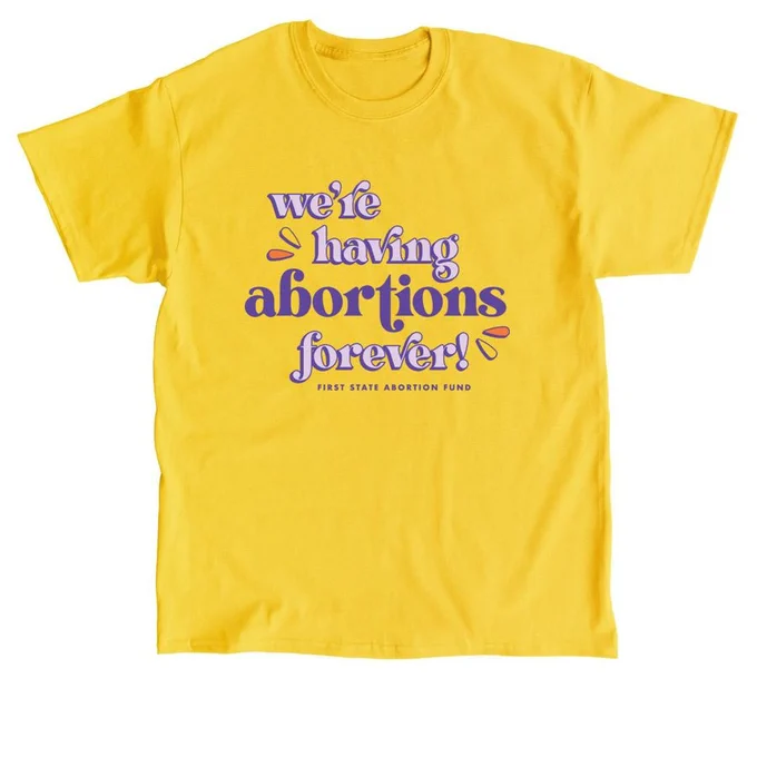 Yellow, short-sleeve t-shirt on a white background. There is purple curly font on the shirt that reads — We're having abortions forever! Below in small text it says First State Abortion Fund. 