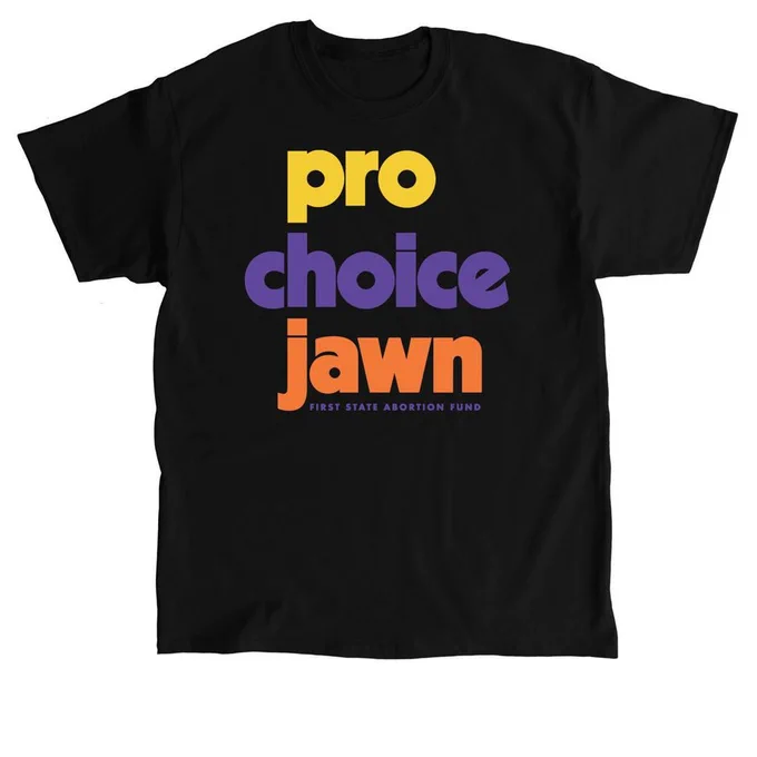 Black short-sleeve t-shirt on a white background. Text on the shirt says "pro choice jawn" in big, bold, lower case letters that are yellow, purple and orange. Below in small font, the shirt says First State Abortion Fund. 