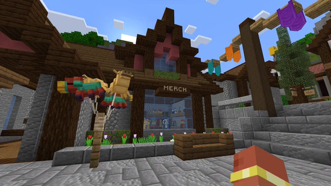 Minecraft screenshot: A building labeled “Merch”, with a sniffer and camel balloons tied to a post outside.